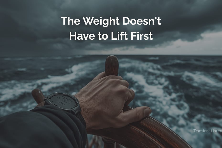 A hand gripping a ship's helm in rough open water under a stormy sky — The Weight Doesn't Have to Lift First